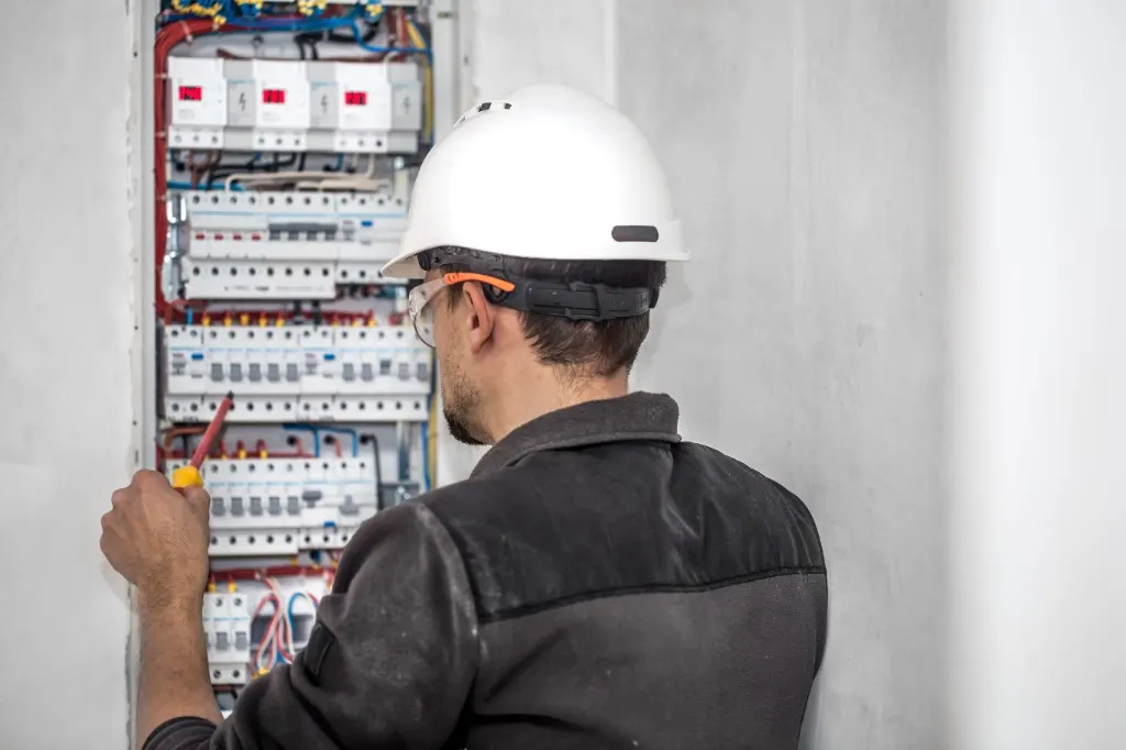 Elektryk pracujący przy domowej rozdzielnicy z zabezpieczeniami